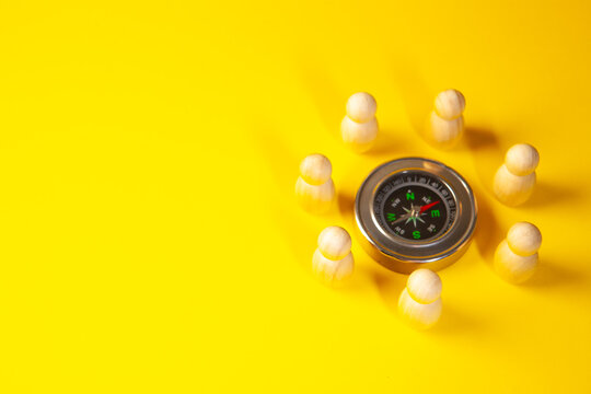 Compass and figures of people on a yellow background. Business concept.