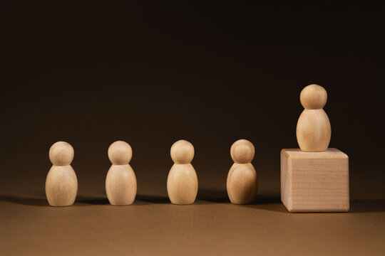 Wooden figures of people stand in a row on a dark background