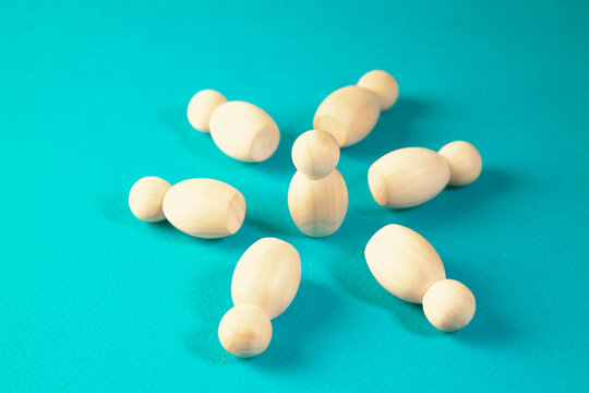 Wooden figures of people on a turquoise background. Shallow depth of field
