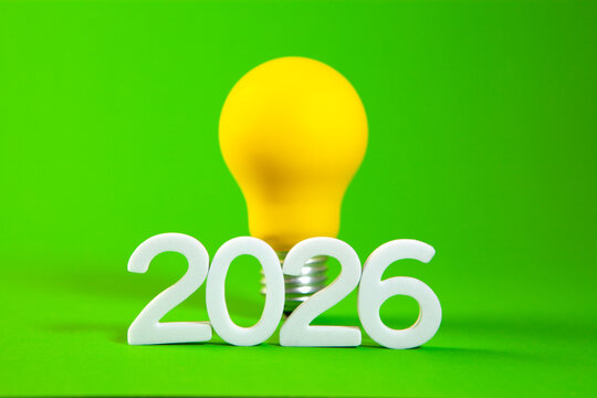 New Year 2026 concept with light bulb on green background.