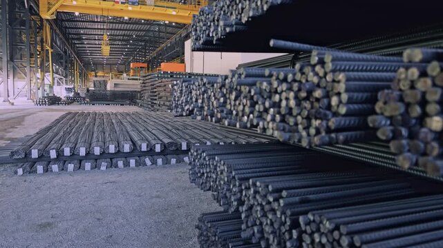 Large bundles of corrugated steel rebars stored inside industrial steel mill warehouse