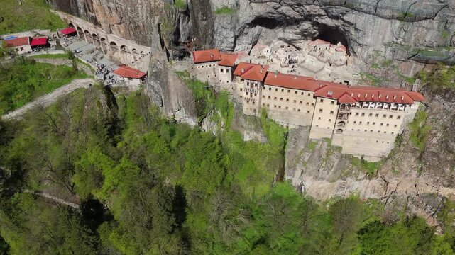drone aerial of the historic Greek Orthodox Sumela Monastery nestled among dense green pine woods in Trabzon, Turkey
