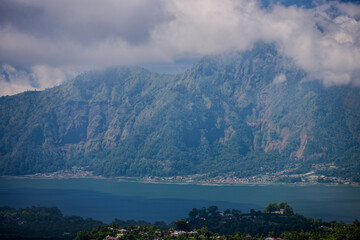 Obraz premium Mount Batur caldera wall rising above the blue waters of Lake Batur in Kintamani
