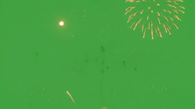 Bright golden fireworks explode against a solid green background screen