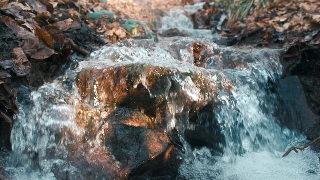 Fresh water of a natural stream flowing in slow motion and pleasant sunlight. Representing life, freshness and a clean environment