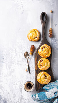 Delicious pastry rolls displayed on a wooden board alongside honey and coffee, creating a warm breakfast atmosphere, phone background with copy space