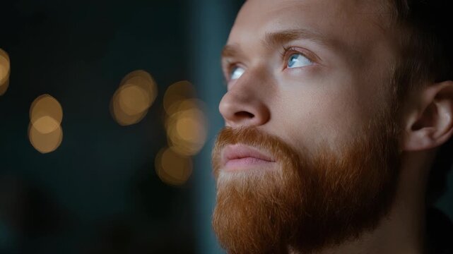 Close-up of a bearded man with well-groomed hair looking contemplative at night