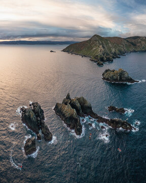 Aerial view of Faro do Cabo Ortegal lighthouse and the jagged Aguillons sea stacks rising from the Atlantic Ocean under a cloudy sky A Coruna, A Coruna, Spain.
