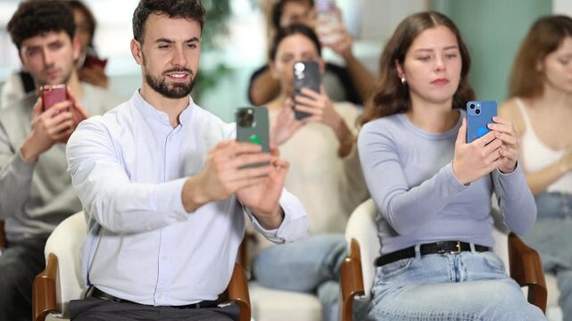 Young learners sitting and scanning QR codes with smartphones in modern educational setting