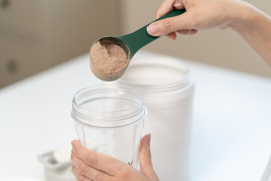 Diet meal replacement for weight loss, asian young woman in sportswear, hand in holding scoop making protein into bottle