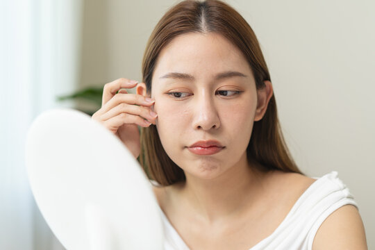 woman have aging on face skin looking at mirror