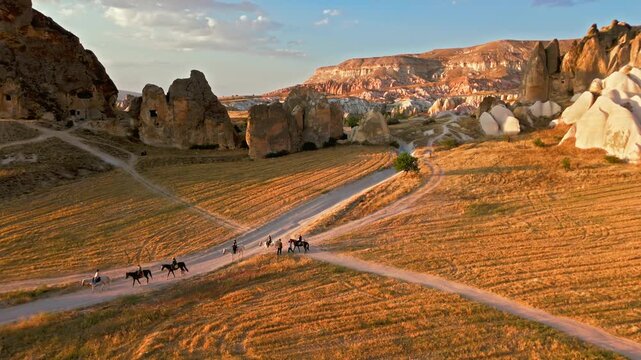 Tourists on a sunset horse riding tour in Rose Valley, Cappadocia. Fairy chimneys, dusty roads and open valleys show a scenic adventure route.