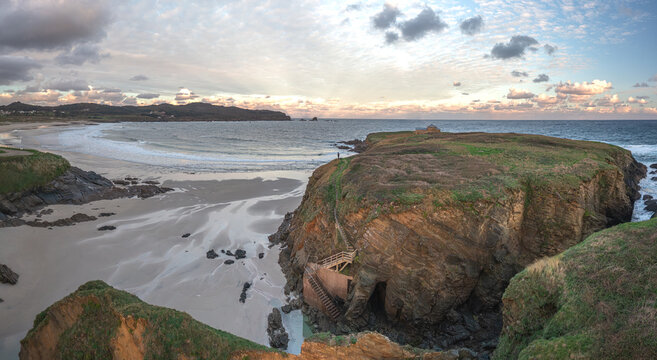 Aerial view of Ermita de Santa Comba on a rocky islet surrounded by sandy beaches and crashing waves under a cloudy sky Covas, La Coruna, Spain.