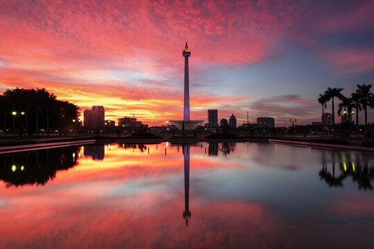 Dramatic blood red sunset and perfect water reflection of the National Monument (Monas) skyline in Jakarta, Indonesia