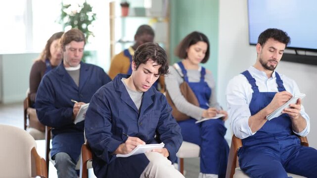 During lecture meeting, group of worker listen to teacher and write down summary. Lecture on changes in labor legislation, trade union meeting, mandatory professional development