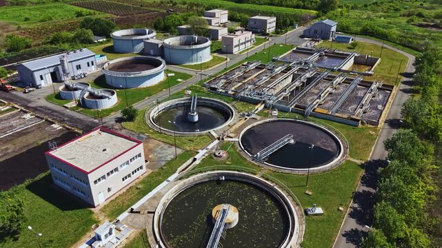 Aerial wastewater treatment plant circular clarifiers, drone perspective over municipal sewage facility with round sedimentation tanks, aeration system,