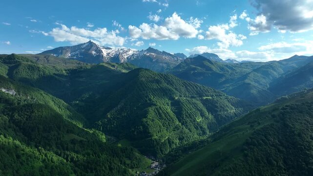 Panorama of green forested Pyrenees valley with snow-capped peaks near Col de Spandelles