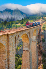 There is a large mountain range in the background with clouds covering the sky - Varda Railway bridge - Adana, Turkey © muratart
