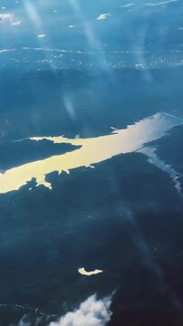 Aerial view of a shimmering river with dragon shape at sunset surrounded by landscapes, vertical video
