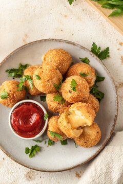 Golden fried cheesy balls with a gooey cheese center served on ceramic plate with fresh parsley leaves garnish and sause top view. Delicious snack for parties or family dinners