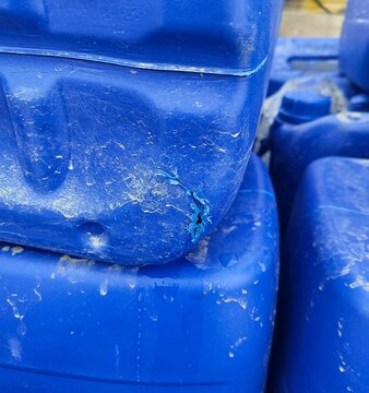 close up of a damaged blue plastic canister with scratches and a bite mark hole showing high density polyethylene pe
