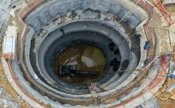 Aerial view of a deep circular excavation shaft with an excavator working at the bottom of the construction site in Avcilar, Istanbul, Turkey.
