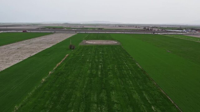 Drone footage showing a large sinkhole surrounded by green agricultural fields. Natural ground collapse, rural terrain, geological formation, and farmland landscape captured from above.