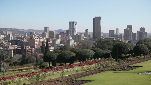Vibrant gardens frame a clear view of Pretoria's cityscape under a bright sky. Ideal for urban landscape features or travel content.