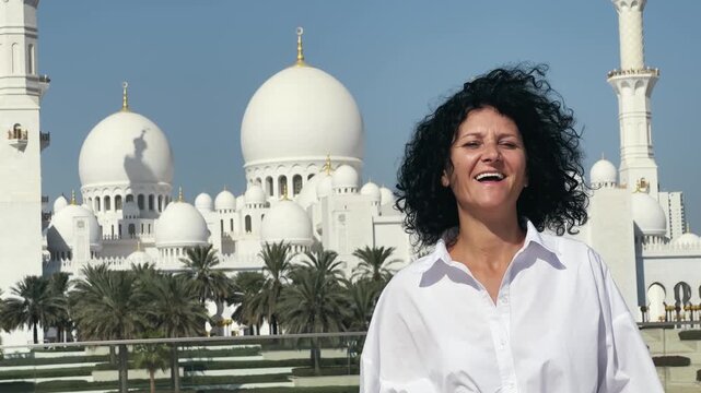 Smiling tourist woman sightseeing Sheikh Zayed Grand Mosque in Abu Dhabi, UAE