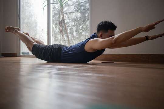 Asian young man doing workout at home - superman exercise