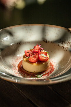 Elegant creme brulee dessert topped with fresh strawberries and caramel sauce on stylish restaurant plate