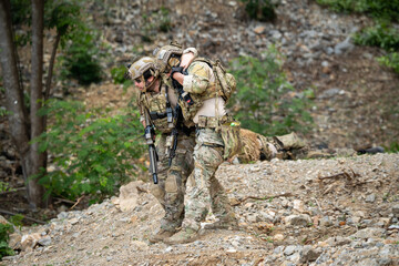 Fototapeta premium Rescue operation soldiers assist injured comrade forested terrain action photography close-up view military valor