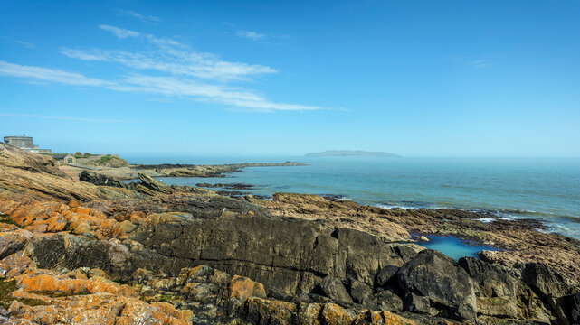 The rocky shoreline of Portrane village on a clear sunny day with views of Lambay Island and the old coastguard station.