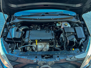 Fototapeta premium Car engine bay shows various parts and components in detail during daylight at a garage or parking area