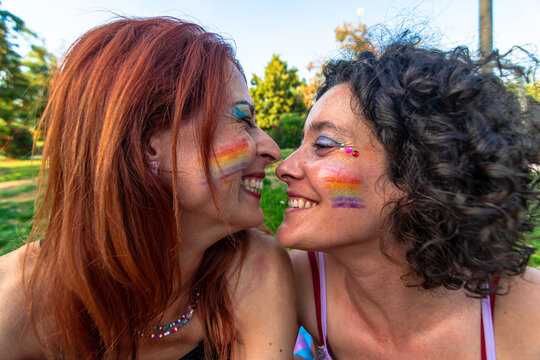 Lesbian couple celebrating pride with rainbow face paint