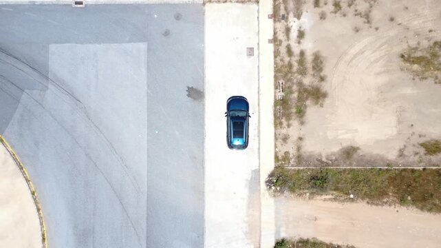 Aerial top down view of a car reversing in a parking lot