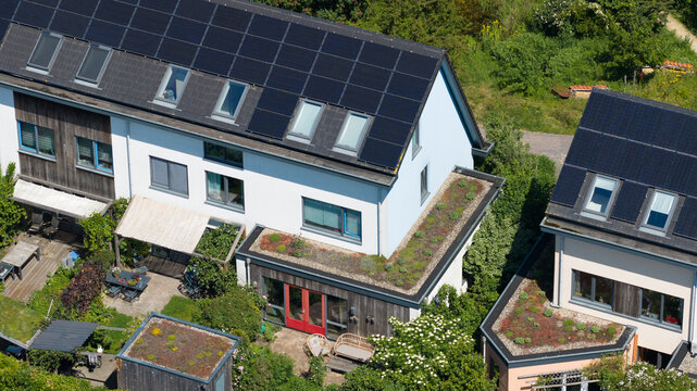 Aerial view of modern residential houses featuring solar panels and green sedum roofs surrounded by lush gardens Houten, Utrecht, Netherlands.