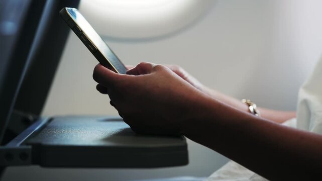 Businesswoman using a smartphone during flight on airplane tray table