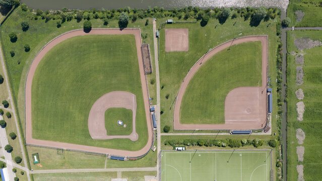Aerial view of baseball and softball fields with green grass and dirt infields at a sports complex surrounded by trees in Houten, Utrecht, Netherlands.