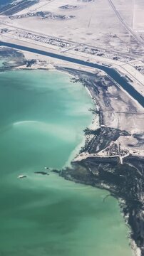 Aerial view of Abu Dhabi coastline with green waters and adjacent infrastructure in UAE