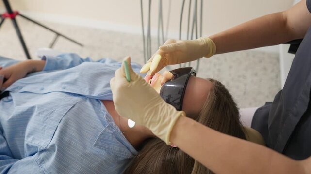Patient lying in dental chair during dental procedure in clinic. Concept of healthcare and preventive care.