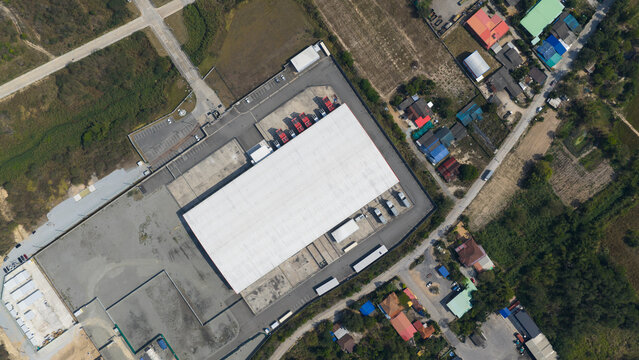 Aerial view of the Data Zone industrial warehouse with trucks at loading docks and surrounding green fields in Khao Khansong, Chon Buri, Thailand.