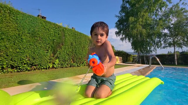 Playful boy shooting water gun at the camera