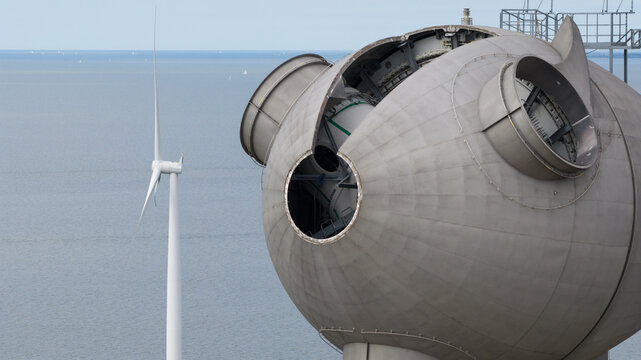 Aerial view of the open hub of a wind turbine nacelle under maintenance with a complete turbine and the sea in the background Espel, Flevoland, Netherlands.