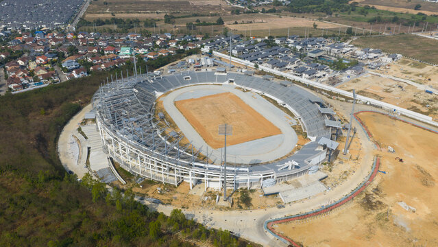 Aerial view of Chaiyaphruek Pattaya Stadium under construction with concrete stands and an oval track surrounded by houses in Muang Pattaya, Chang Wat Chon Buri, Thailand.