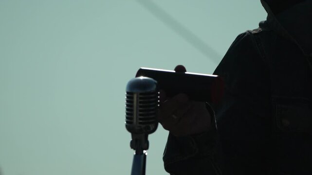Microphone shaker musician performs on stage with a vintage mic and hand percussion creating an atmospheric and rhythmic performance