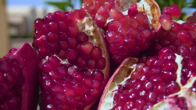 Panorama view of cleaned pomegranates with juicy seeds falling onto them against a blue sky background. Vitamins, diet, healthy eating