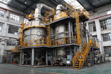 Naklejka premium Interior view of a modern industrial facility with large processing tanks, interconnected pipes, and yellow safety railings