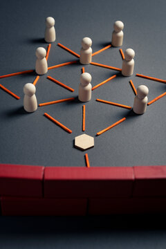 Wooden pawns blocked by a brick wall representing corporate constraints