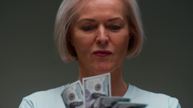 Old Caucasian woman counts the cash one hundred in hands, banknotes. Senior female holds paper money USD dollars in palms, with money deficit. Utility Bills Payment earnings. Elderly lady counting.